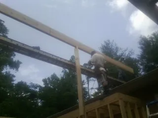 Carpenter setting a ridge beam over a new addition frame — Ice Dam Removal by Roofing Brothers in Savage