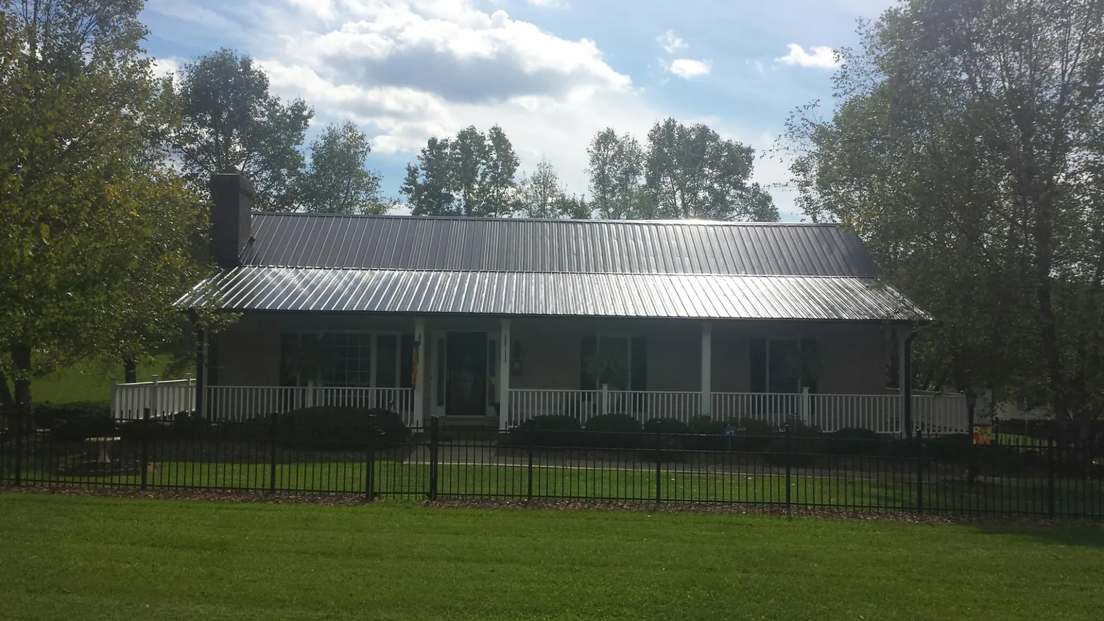 Gray metal roof on a brick ranch with a full width front porch — Gutter Guard Installation work by our crew in Savage