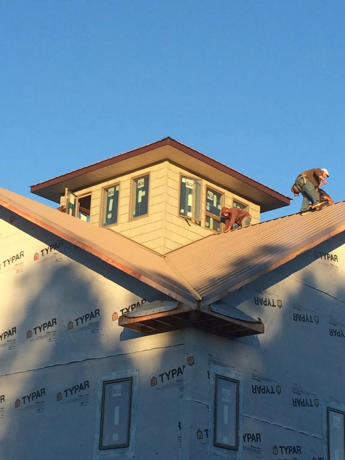 Roofers working around a rooftop cupola on a new metal roof at sunset — Roof Waterproofing in Savage by Roofing Brothers